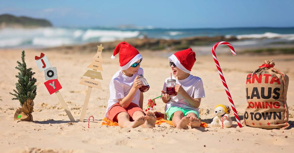 Two,Young,Boys,In,Christmas,Caps,Sitting,On,The,Beach,