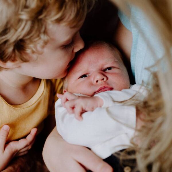 A,Small,Boy,Kissing,A,Newborn,Baby,Brother,At,Home.